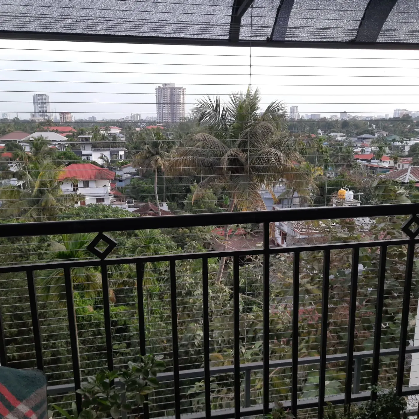 Invisible stainless-steel balcony grill installed on a Kerala home, existing railing visible